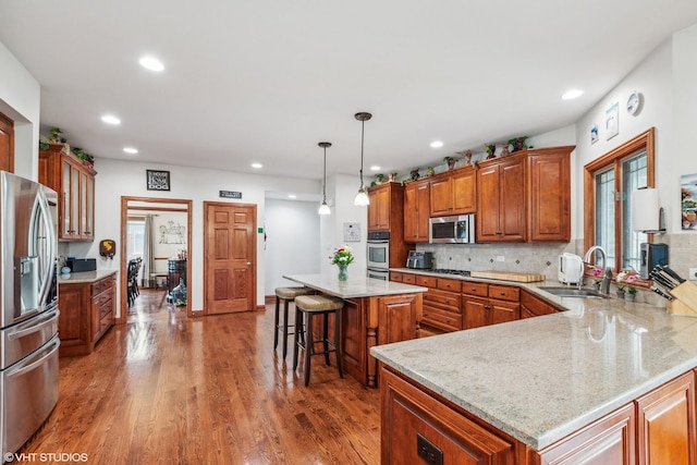 9265 Maura Ct, Frankfort, IL 60423 - kitchen with appliances with stainless steel finishes, brown cabinetry, a breakfast bar, wood finished floors, and recessed lighting