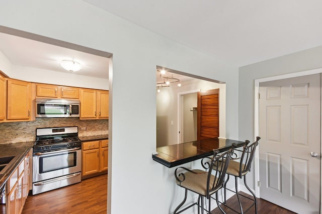 493 Mchenry Rd Unit 1B, Wheeling, IL 60090 - kitchen featuring appliances with stainless steel finishes, dark wood-style floors, dark countertops, and backsplash