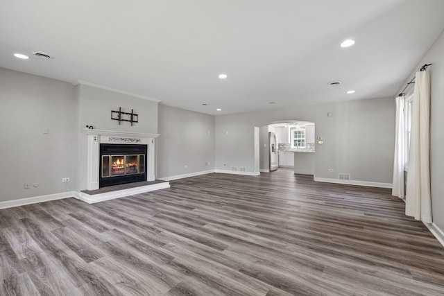 10409 S 83rd Ave, Palos Hills, IL 60465 - unfurnished living room with arched walkways, wood finished floors, recessed lighting, and a glass covered fireplace