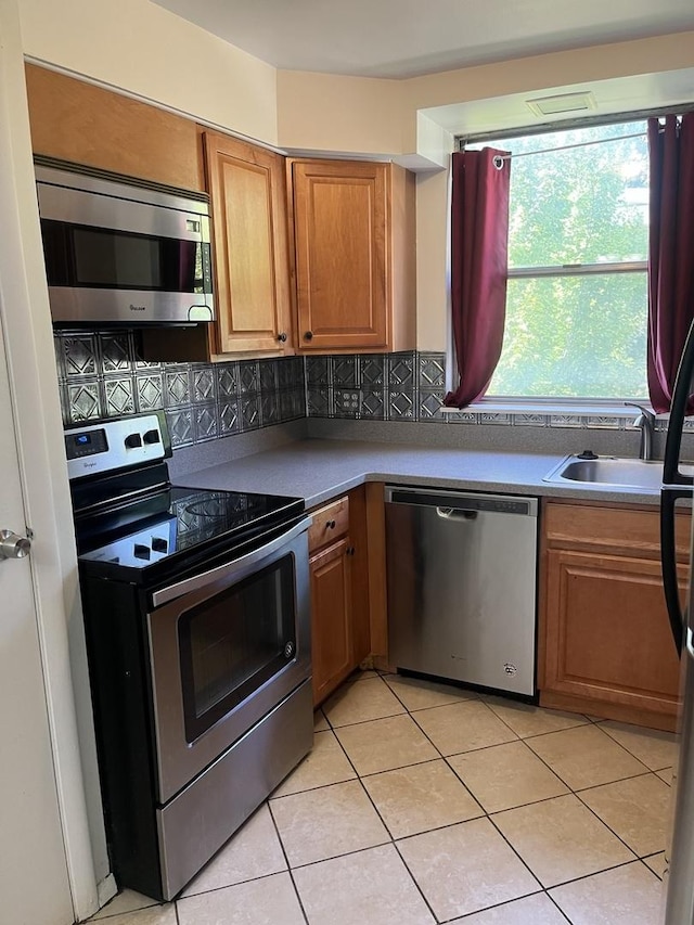 415 Wesley Ave Unit 21, Oak Park, IL 60302 - kitchen featuring stainless steel appliances, backsplash, light tile patterned floors, and brown cabinetry