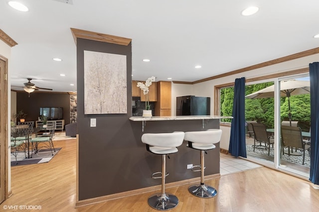 609 N Eastman Dr, Mount Prospect, IL 60056 - kitchen featuring freestanding refrigerator, ornamental molding, a kitchen breakfast bar, light wood finished floors, and a peninsula