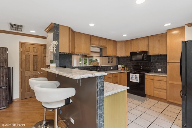 609 N Eastman Dr, Mount Prospect, IL 60056 - kitchen featuring black appliances, a peninsula, decorative backsplash, a kitchen bar, and recessed lighting