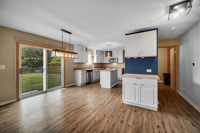 352 Westport Dr, Pingree Grove, IL 60140 - kitchen with a center island, wood finished floors, appliances with stainless steel finishes, white cabinets, and decorative light fixtures
