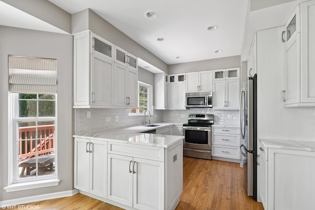 6162 Crossland Blvd, Gurnee, IL 60031 - kitchen with appliances with stainless steel finishes, a peninsula, decorative backsplash, light wood-style flooring, and white cabinetry