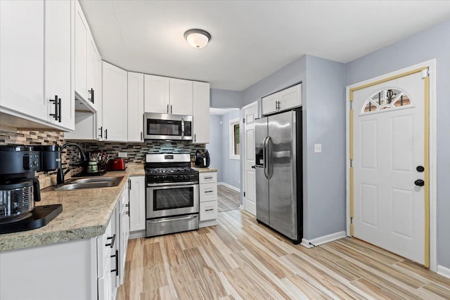 15117 Madison Ave, Dolton, IL 60419 - kitchen featuring appliances with stainless steel finishes, decorative backsplash, light countertops, white cabinets, and light wood-style flooring
