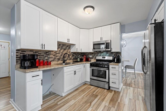 15117 Madison Ave, Dolton, IL 60419 - kitchen featuring appliances with stainless steel finishes, light wood-type flooring, backsplash, and white cabinetry
