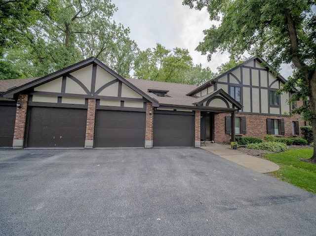 8125 Willow Dr Unit C, Palos Hills, IL 60465 - tudor house featuring a garage, asphalt driveway, brick siding, and stucco siding