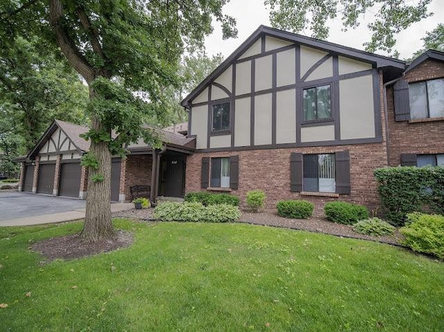 8125 Willow Dr Unit C, Palos Hills, IL 60465 - tudor-style house with brick siding, a front lawn, stucco siding, driveway, and a garage