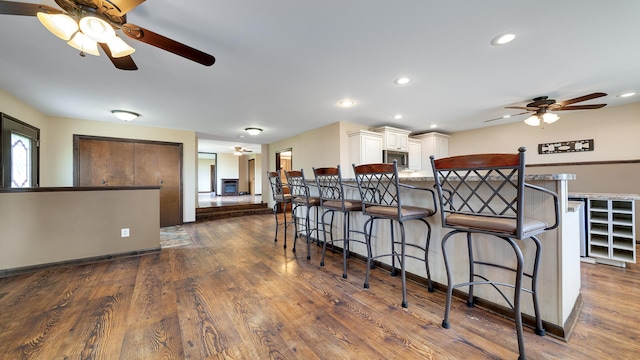 18521 Anderson Rd, Prophetstown, IL 61277 - kitchen with a ceiling fan, a kitchen bar, stainless steel microwave, dark wood-style floors, and a peninsula