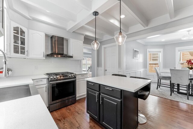 2610 N Major Ave, Chicago, IL 60639 - kitchen featuring stainless steel range with gas cooktop, wall chimney range hood, white cabinets, a breakfast bar area, and light countertops