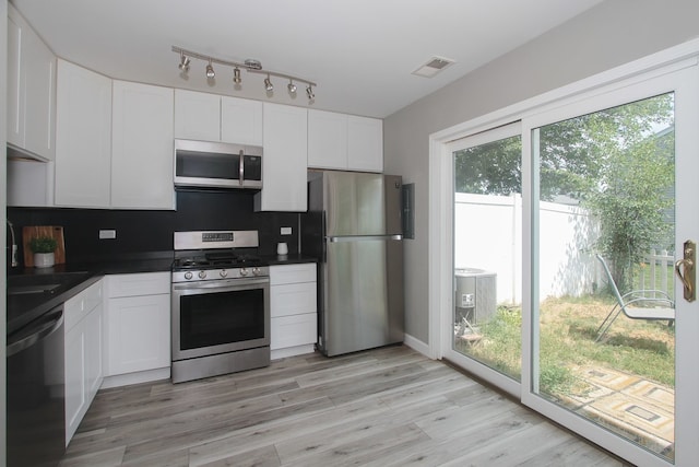 446 Northampton Ln, Roselle, IL 60172 - kitchen with stainless steel appliances, dark countertops, white cabinets, light wood-style floors, and tasteful backsplash