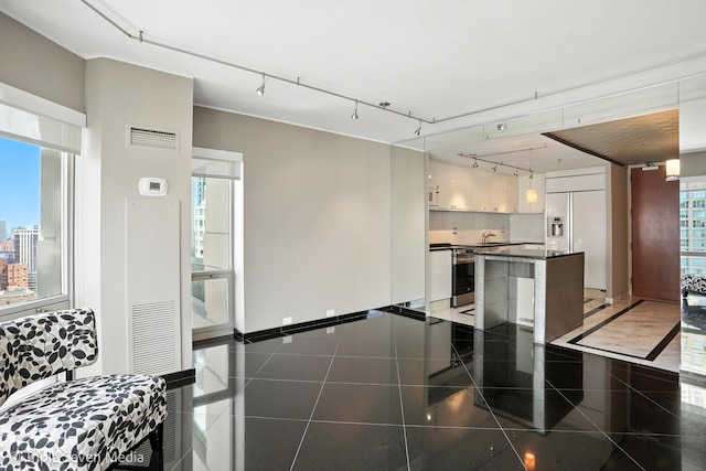 100 E Huron St Unit 2301, Chicago, IL 60611 - kitchen with dark countertops, paneled fridge, stainless steel electric range oven, white cabinetry, and rail lighting