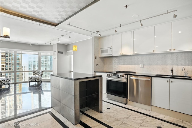 100 E Huron St Unit 2301, Chicago, IL 60611 - kitchen featuring appliances with stainless steel finishes, inlaid floor details, rail lighting, dark countertops, and white cabinets