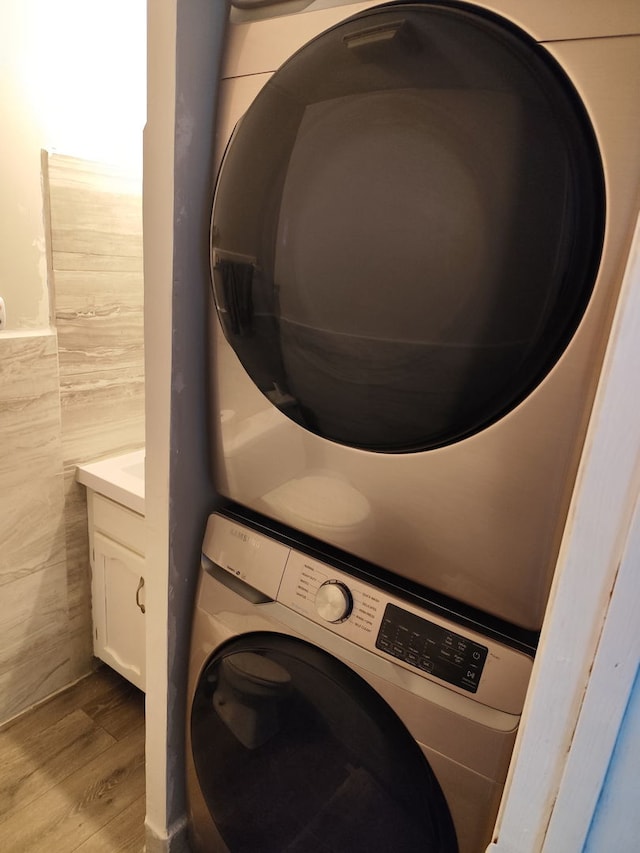 438 Meadow Hill Ln, Round Lake Beach, IL 60073 - washroom featuring stacked washing machine and dryer, wood finished floors, cabinet space, and tile walls