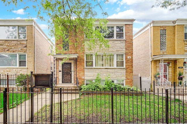 5567 W Gladys Ave, Chicago, IL 60644 - view of front facade featuring a fenced front yard and stone siding