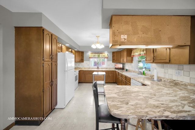 506 S 5th St, Malta, IL 60150 - kitchen featuring white appliances, a peninsula, a chandelier, brown cabinetry, and tasteful backsplash