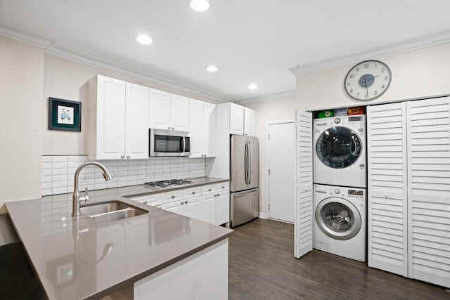 1801 W Diversey Pkwy Unit 36, Chicago, IL 60614 - kitchen with appliances with stainless steel finishes, stacked washer / dryer, ornamental molding, a peninsula, and backsplash