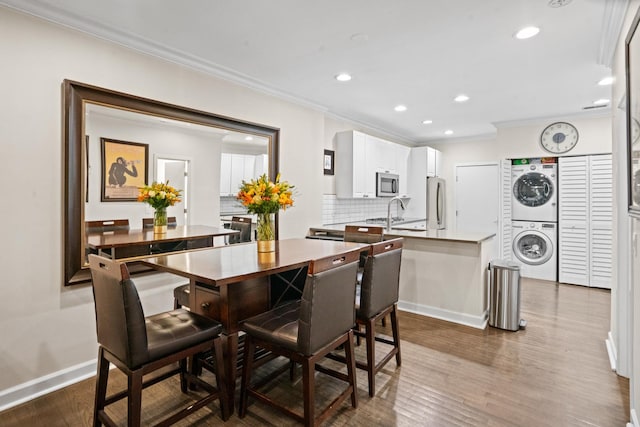 1801 W Diversey Pkwy Unit 36, Chicago, IL 60614 - dining area with stacked washing machine and dryer, ornamental molding, dark wood-style floors, and recessed lighting