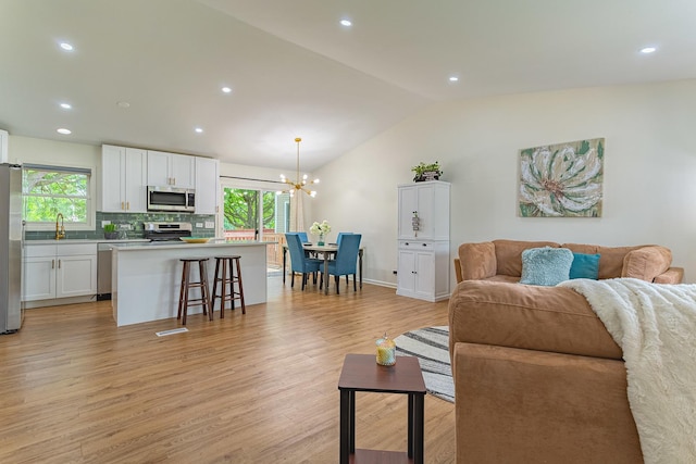 7559 Kingsbury Dr, Hanover Park, IL 60133 - living area featuring lofted ceiling, light wood-type flooring, a chandelier, plenty of natural light, and recessed lighting