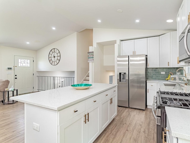 7559 Kingsbury Dr, Hanover Park, IL 60133 - kitchen featuring appliances with stainless steel finishes, light wood-style flooring, a center island, lofted ceiling, and white cabinetry