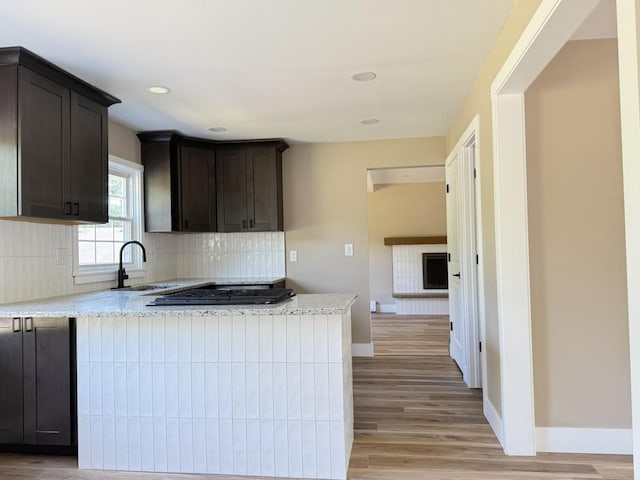 3814 Abbotsford Rd, Rockford, IL 61107 - kitchen featuring gas stovetop, tasteful backsplash, light wood-style floors, dark brown cabinets, and a peninsula
