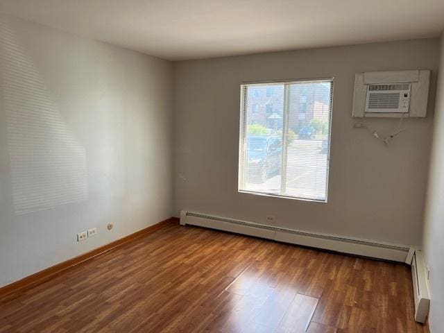 291 Gregory St Unit 6, Aurora, IL 60504 - empty room with a baseboard radiator, a wall mounted air conditioner, wood finished floors, and a baseboard heating unit