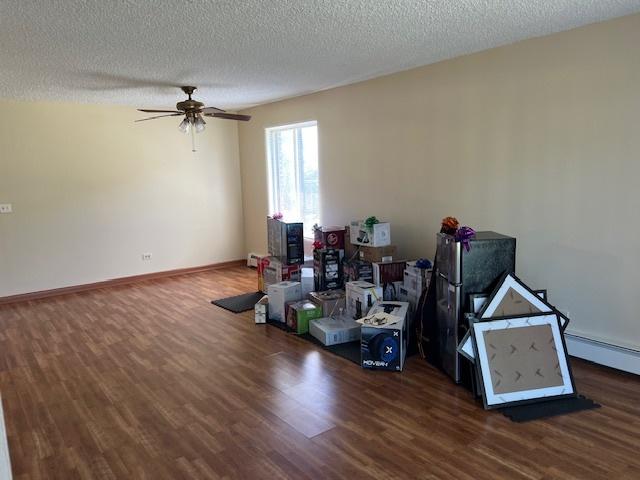 291 Gregory St Unit 6, Aurora, IL 60504 - empty room with wood finished floors, ceiling fan, a textured ceiling, and a baseboard heating unit
