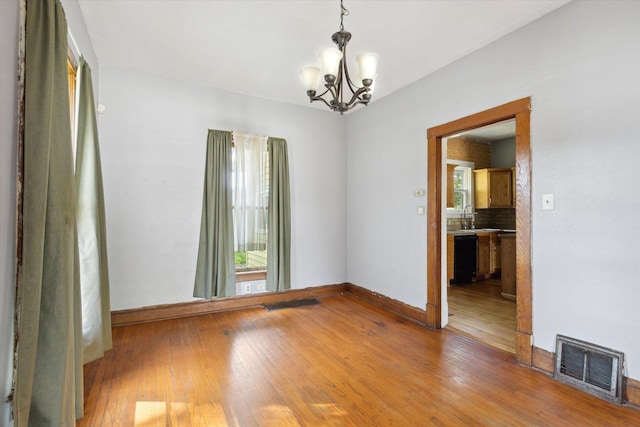 1304 E 4th St, Sterling, IL 61081 - unfurnished room featuring a chandelier, healthy amount of natural light, and hardwood / wood-style flooring