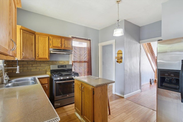 1304 E 4th St, Sterling, IL 61081 - kitchen with appliances with stainless steel finishes, under cabinet range hood, light wood-style floors, pendant lighting, and tasteful backsplash