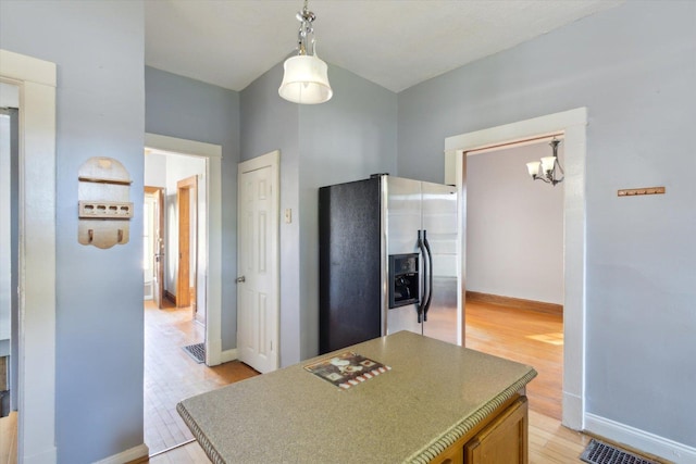 1304 E 4th St, Sterling, IL 61081 - kitchen with stainless steel fridge with ice dispenser, light wood-style flooring, a chandelier, a center island, and decorative light fixtures