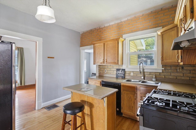 1304 E 4th St, Sterling, IL 61081 - kitchen featuring appliances with stainless steel finishes, a kitchen island, light wood-style flooring, extractor fan, and light countertops