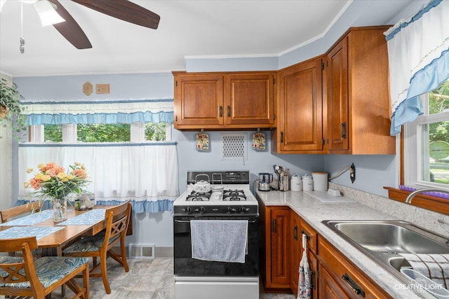 393 Lakelawn Blvd, Aurora, IL 60506 - kitchen featuring range with gas stovetop, a ceiling fan, brown cabinetry, and light countertops
