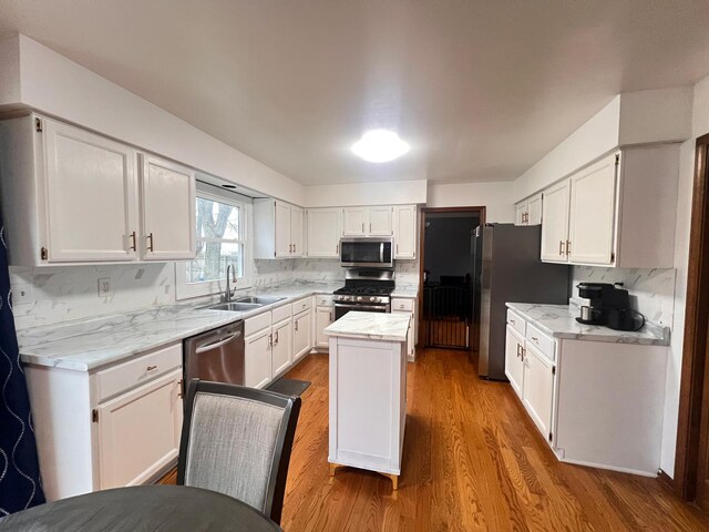 1970 Division St, Saint Charles, IL 60174 - kitchen featuring stainless steel appliances, wood finished floors, white cabinets, a kitchen island, and light stone countertops