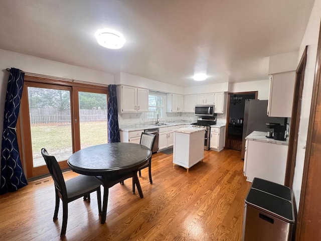 1970 Division St, Saint Charles, IL 60174 - kitchen with appliances with stainless steel finishes, a center island, white cabinets, light countertops, and light wood-style floors