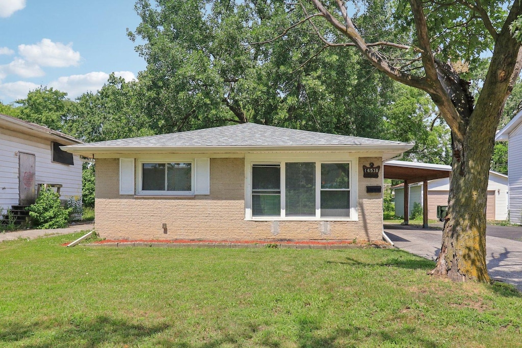 16538 Park Ave, Markham, IL 60428 - view of front of house with a front lawn, a carport, a shingled roof, and brick siding