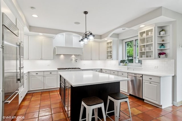 366 W Eggleston Ave, Elmhurst, IL 60126 - kitchen featuring appliances with stainless steel finishes, backsplash, a kitchen bar, a center island, and arched walkways