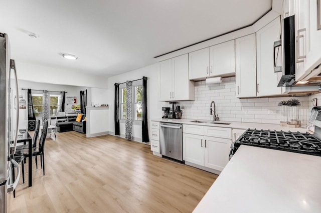 1030 Spruce St, Aurora, IL 60506 - kitchen with appliances with stainless steel finishes, light countertops, decorative backsplash, white cabinetry, and light wood finished floors