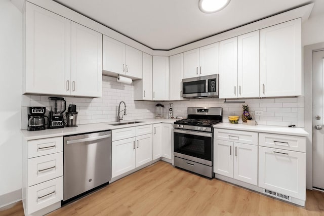1030 Spruce St, Aurora, IL 60506 - kitchen with stainless steel appliances, light countertops, decorative backsplash, light wood finished floors, and white cabinets