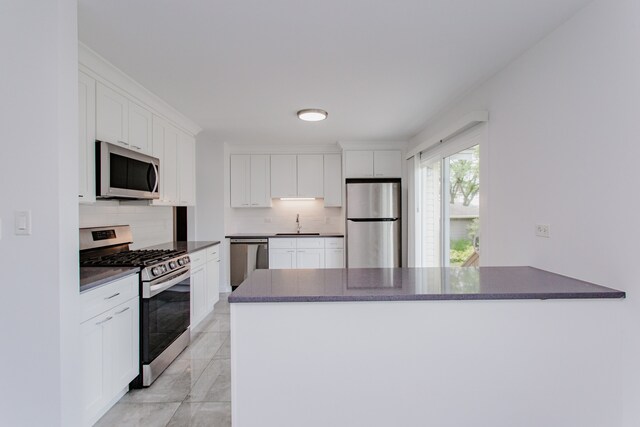 815 Concord Cv, Hoffman Estates, IL 60192 - kitchen with appliances with stainless steel finishes, dark countertops, decorative backsplash, and white cabinets