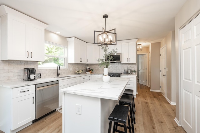 25030 Round Barn Rd, Plainfield, IL 60585 - kitchen with appliances with stainless steel finishes, a chandelier, a kitchen bar, decorative backsplash, and white cabinets