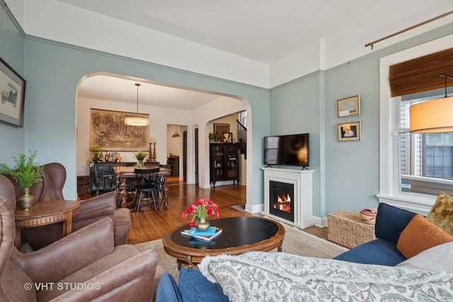 5747 W Grace St, Chicago, IL 60634 - living room featuring arched walkways, wood finished floors, and a lit fireplace