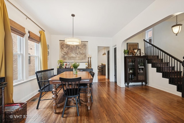 5747 W Grace St, Chicago, IL 60634 - dining area featuring arched walkways, dark wood finished floors, and stairs
