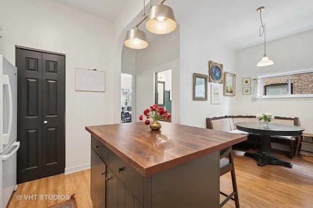 5747 W Grace St, Chicago, IL 60634 - kitchen with butcher block countertops, light wood-style floors, freestanding refrigerator, pendant lighting, and arched walkways