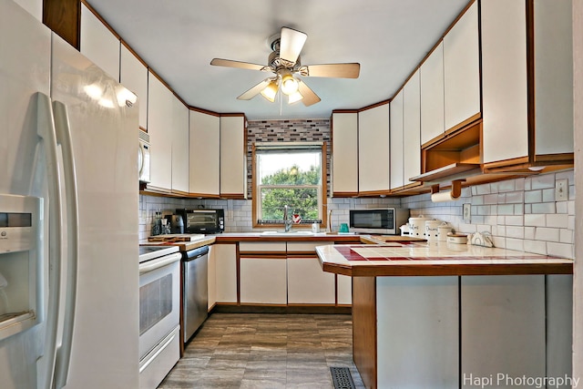 1912 Oak Dr, Mchenry, IL 60050 - kitchen with stainless steel appliances, a peninsula, dark wood finished floors, tasteful backsplash, and a ceiling fan
