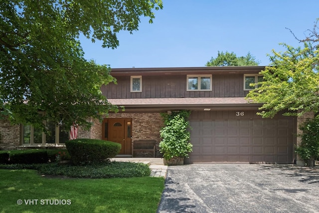 36 Logan Ter, Golf, IL 60029 - view of front of house with an attached garage, asphalt driveway, brick siding, and a front lawn