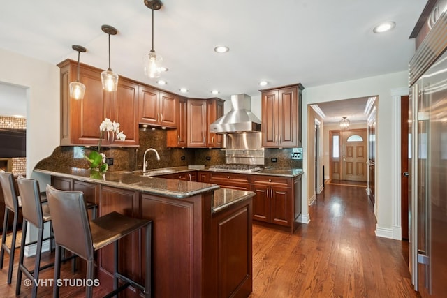 36 Logan Ter, Golf, IL 60029 - kitchen with wall chimney exhaust hood, a peninsula, dark stone countertops, decorative light fixtures, and tasteful backsplash