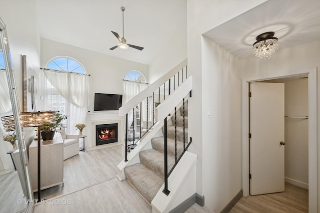 707 Sturnbridge Ln, Schaumburg, IL 60173 - stairs featuring wood finished floors, a lit fireplace, ceiling fan, a chandelier, and a high ceiling
