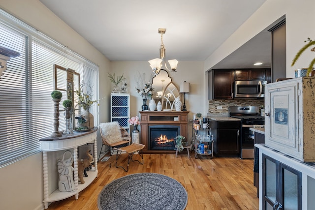 641 Sundance Dr, Bolingbrook, IL 60440 - dining room with light wood-style flooring, a lit fireplace, and a chandelier