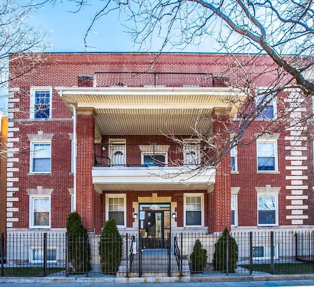 4137 S Prairie Ave Unit 1S, Chicago, IL 60653 - view of front facade featuring a balcony, brick siding, and a fenced front yard