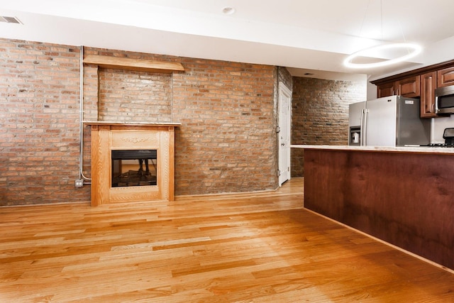 4137 S Prairie Ave Unit 1S, Chicago, IL 60653 - kitchen featuring stainless steel appliances, brick wall, light wood finished floors, a multi sided fireplace, and light countertops